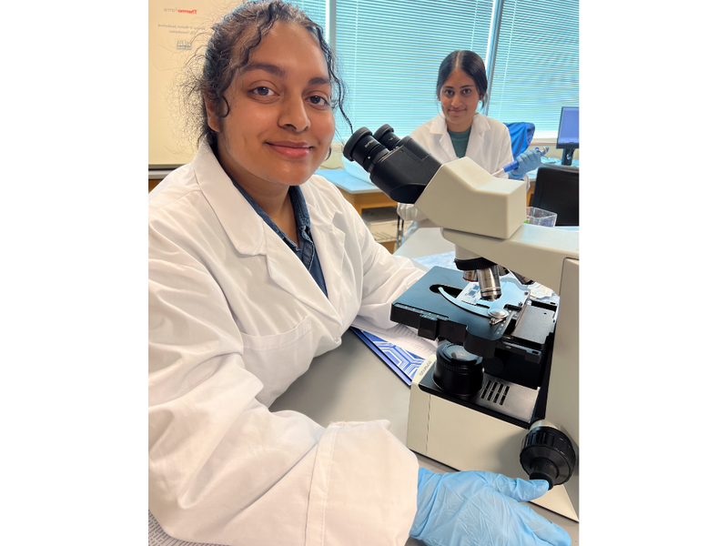 Two female biologists using microscopes